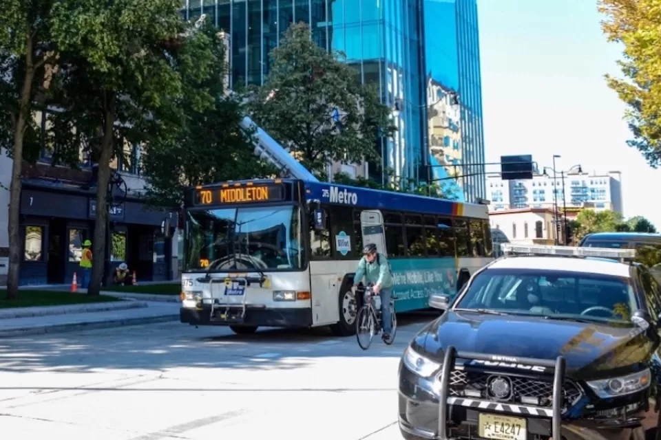 Public transit bus on street with cyclist riding next to it in Madison, Wisconsin.